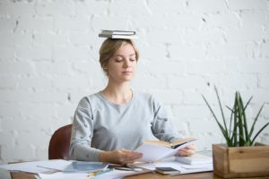 lady sitting upright balancing book on head